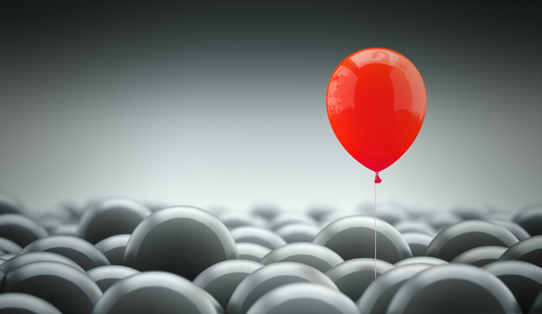 Different, unique and standing out of the crowd concept. A red baloon is different and above the other gray ones, representing the individuality in the masses.