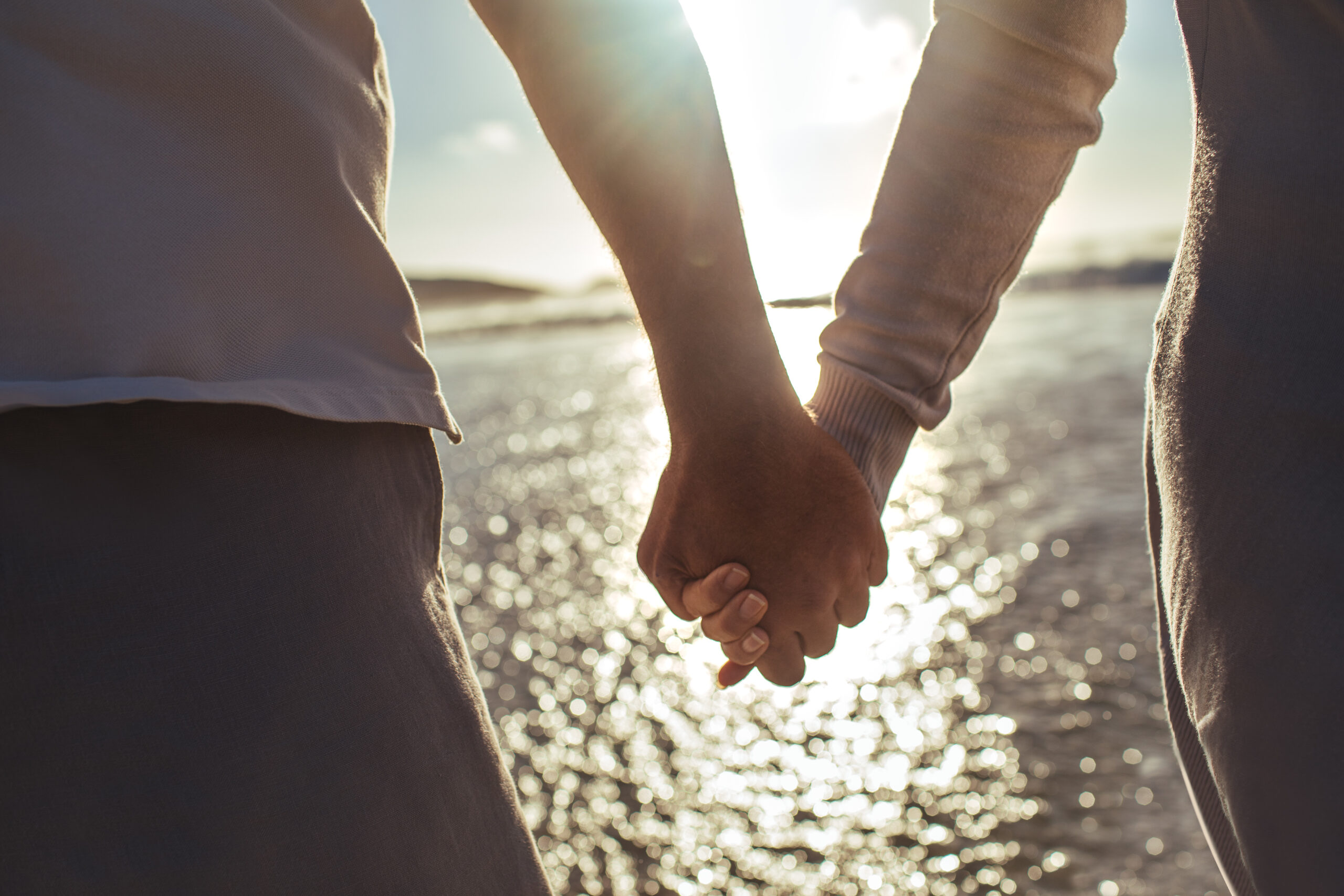 Cropped shot of an older couple holding hands at the beach