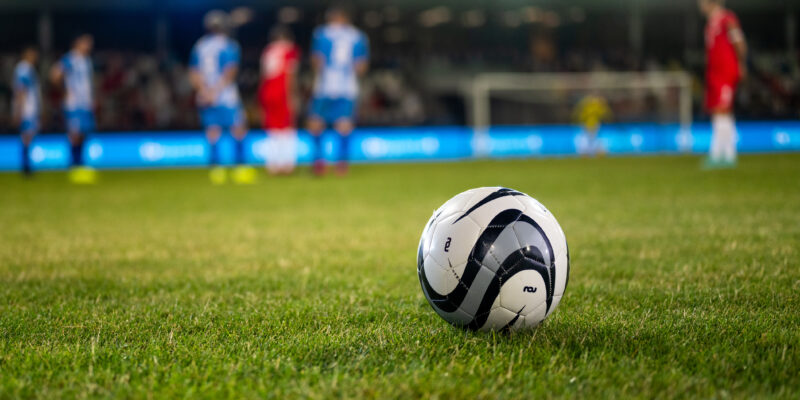 Football kept on grassy football pitch.
